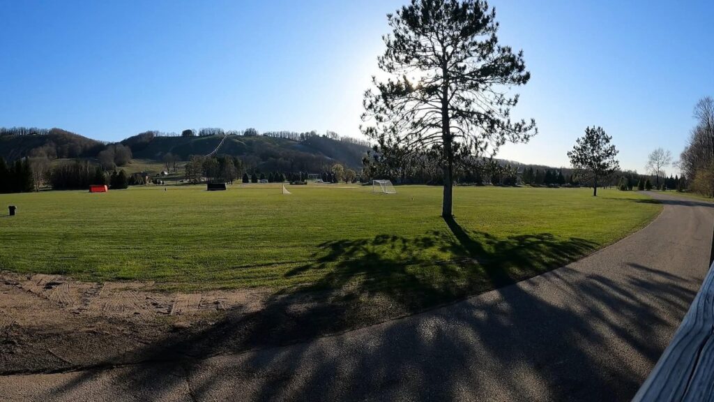 View of Boyne Mountain in spring with green grass and budding trees.