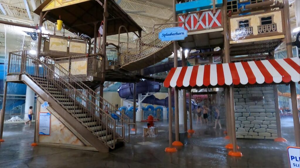 Colourful Splasherhorn Play Structure at Avalanche Bay Indoor Waterpark, featuring water cannons, slides, and a giant tipping water bucket — perfect for kids and families.