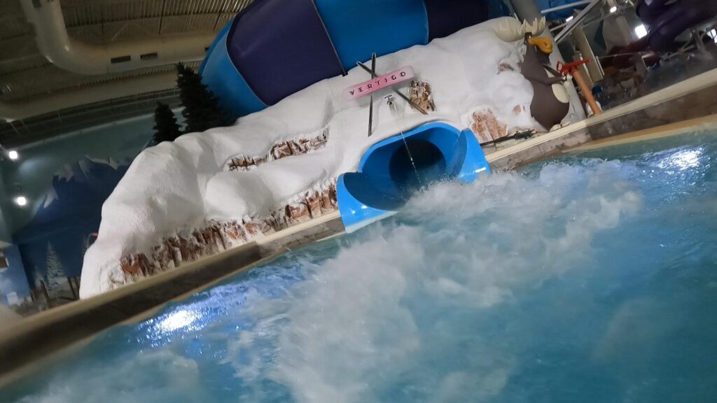 Rider swirling through the giant Vertigo Cannonbowl slide at Avalanche Bay Indoor Waterpark — an adrenaline-pumping ride that spins you around a massive bowl before a splash landing.