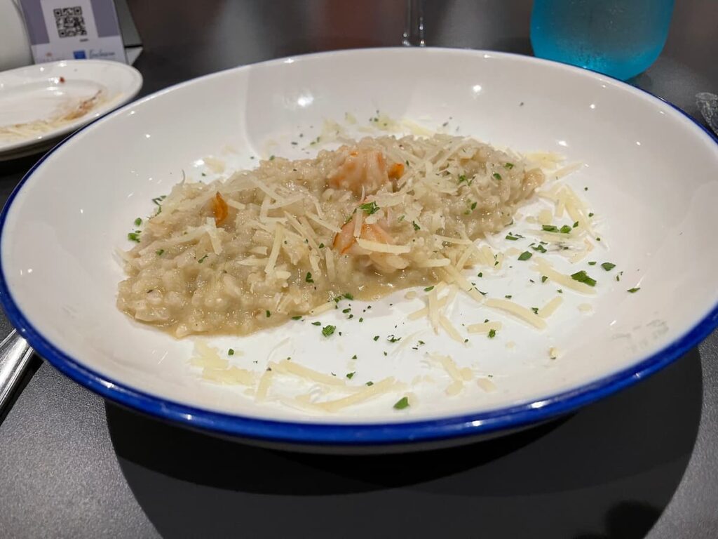 Creamy risotto dish served at Portofino Italian restaurant at Dreams Flora, garnished with herbs and Parmesan cheese.