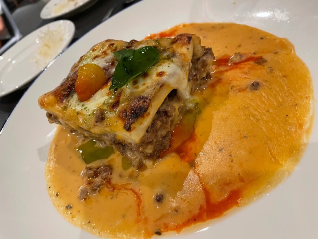 Close-up of baked lasagna served at Portofino Italian restaurant at Dreams Flora, topped with melted cheese and marinara sauce.