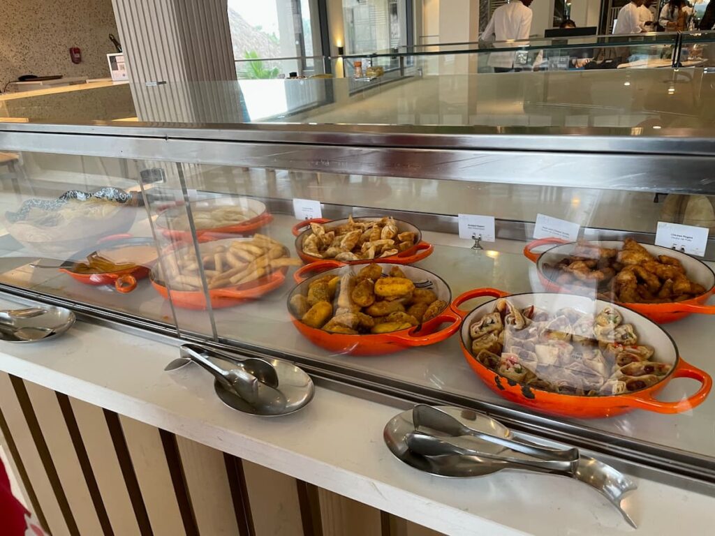 Snack selection at the Preferred Club Lounge featuring hot appetizers, fresh vegetables, and dips in a stylish setting.