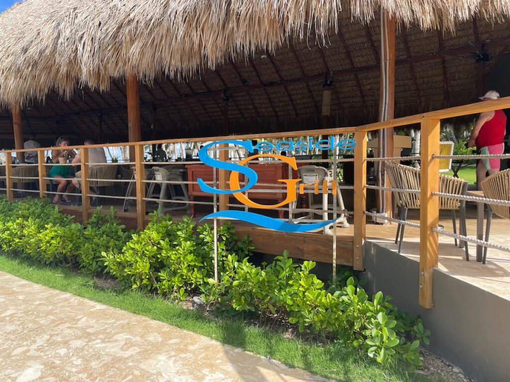 Outdoor seating area at Seaside Grill in Dreams Flora overlooking the beach, with ocean views and tropical ambiance.