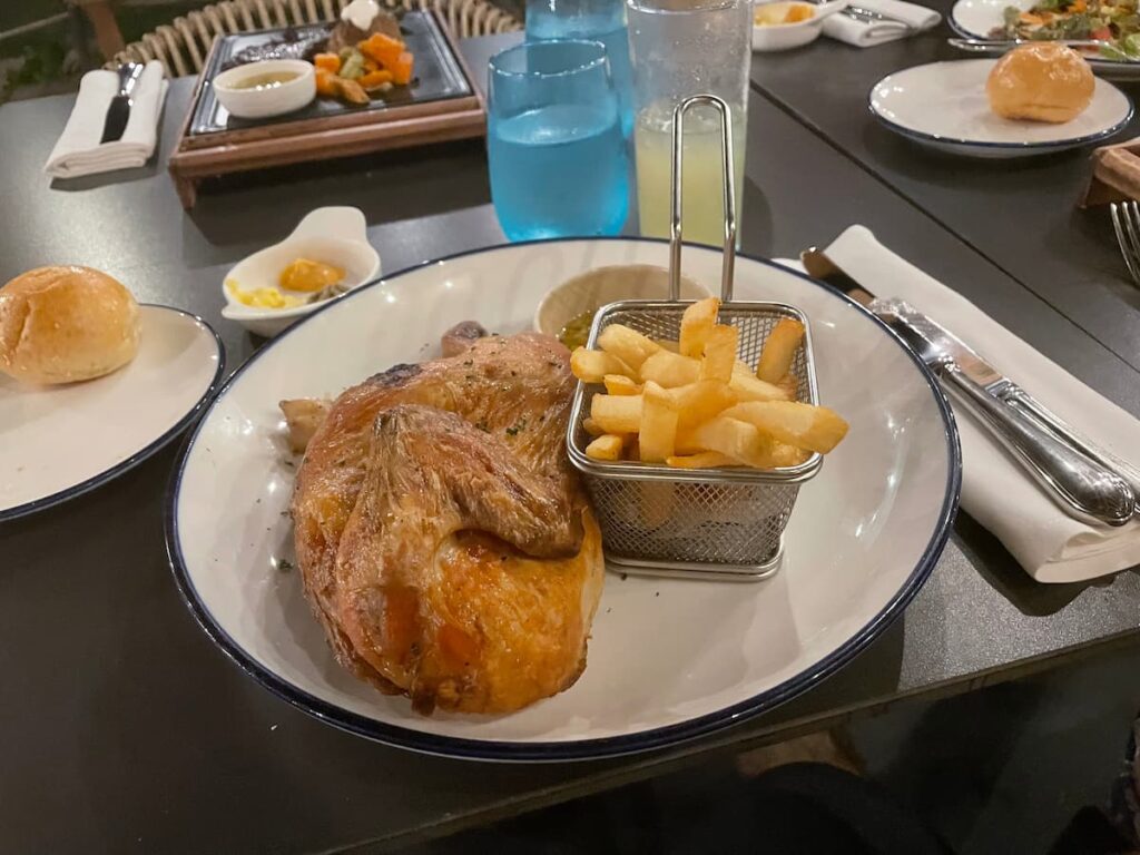 Grilled chicken breast served with vegetables and mashed potatoes on a white plate at Dreams Flora.