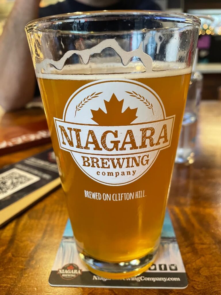 Craft beer served in a branded glass at Niagara Brewing Company with a frothy head and inviting presentation.