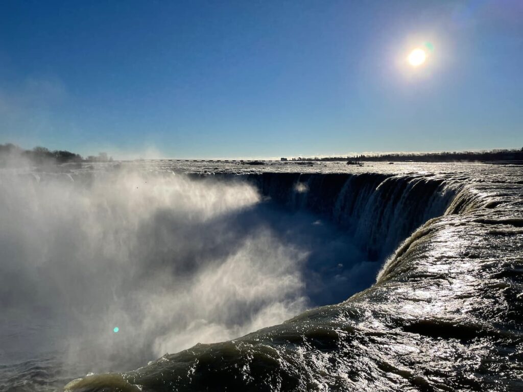 Majestic view of Niagara Falls with powerful cascades of water plunging over the cliffs and mist rising into the air.